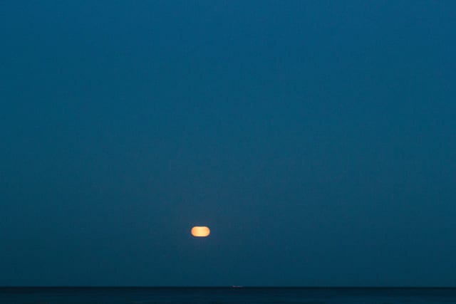 A full moon in the center, as a blurry streak.