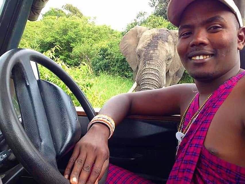 An Out2safari guide at the wheel with an elephant beside the vehicle