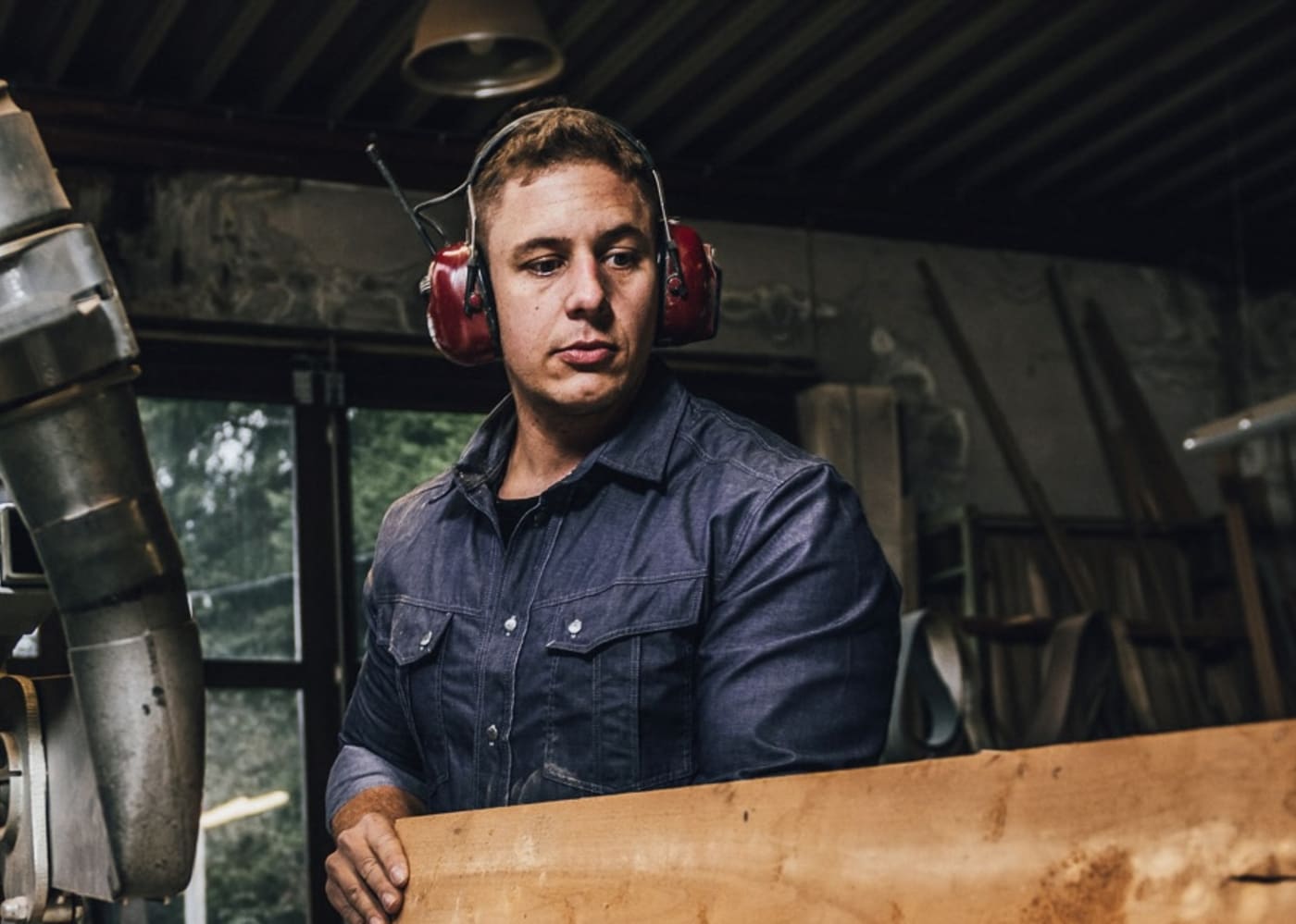 A portrait of master carpenter Matthias Steffens in his workshop wearing hearing protection.