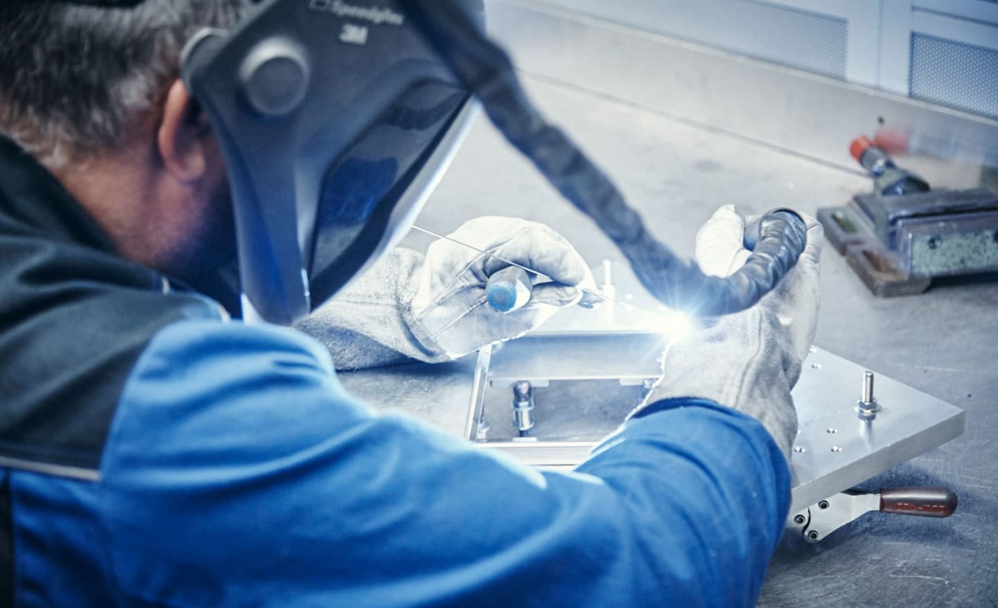 Mitarbeiter schweißt in der FSB Produktion in Brakel einen Türdrücker von Hand.