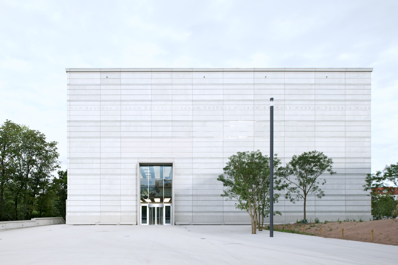 Frontal view of the Bauhaus Museum Weimar with clear, minimalist concrete facade and central entrance.