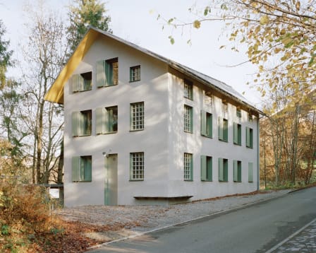 Apartment building on Sittertalstrasse in St. Gallen, a white-rendered replacement building with green shutters at the edge of the forest.