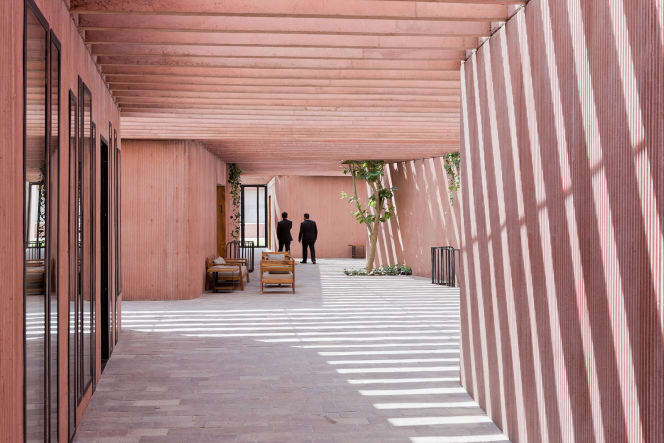 Sunlit courtyard of the Tangassi Funeral Home in San Luis Potosí, Mexico, featuring pink-tinted concrete walls and a dramatic play of shadows. Architecture by Tatiana Bilbao. Photo by Iwan Baan.