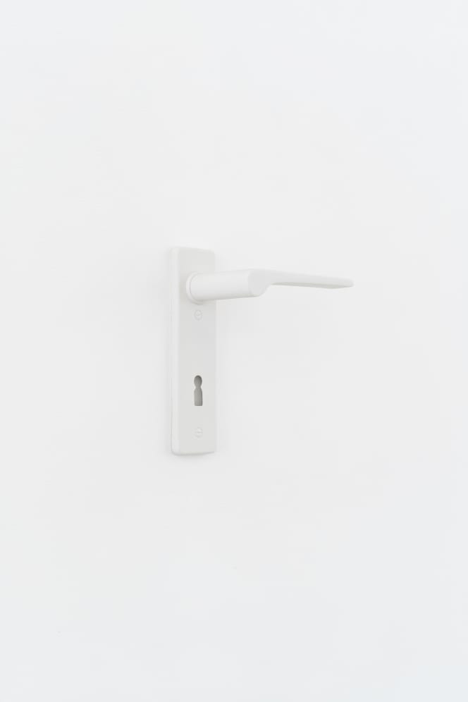 White door lever with a long backplate and keyhole in unglazed porcelain from Friedemann Heckel’s “Open Doors” exhibition.