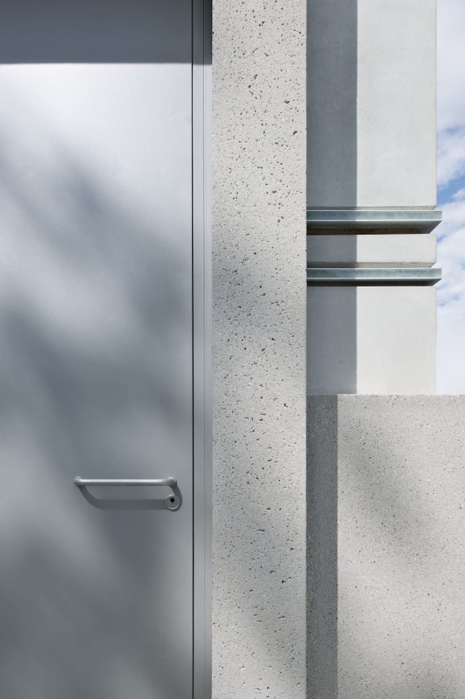 Minimalist grey door with FSB 1147 Wittgenstein Aluminum Pure handle, set in the concrete architecture of the Bauhaus Museum Weimar.