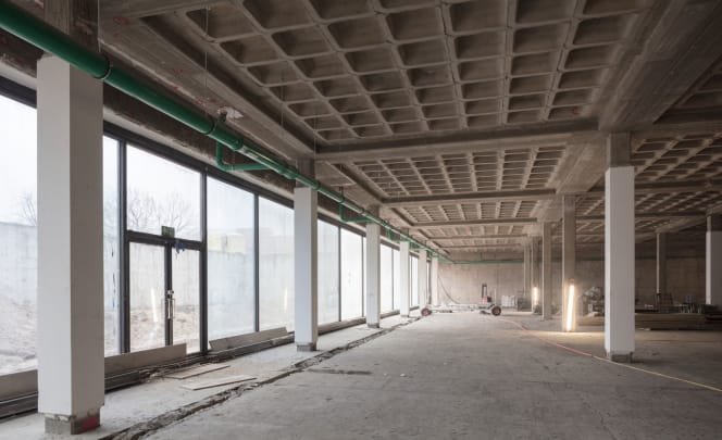 A photo of the garden hall on the lower floor during renovations is shown here. For the renovation, the building was practically stripped down to its raw structure and all installations such as doors, ceiling cladding and flooring were put into storage.