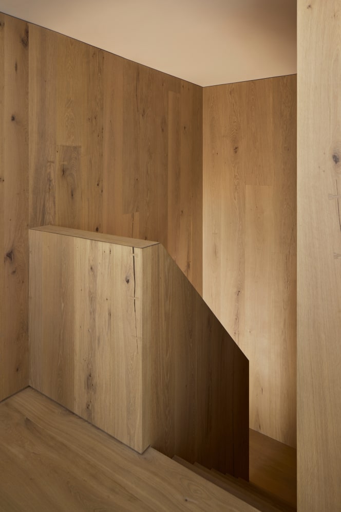 A view of a minimalist staircase, which is entirely clad in honey-brown wood.