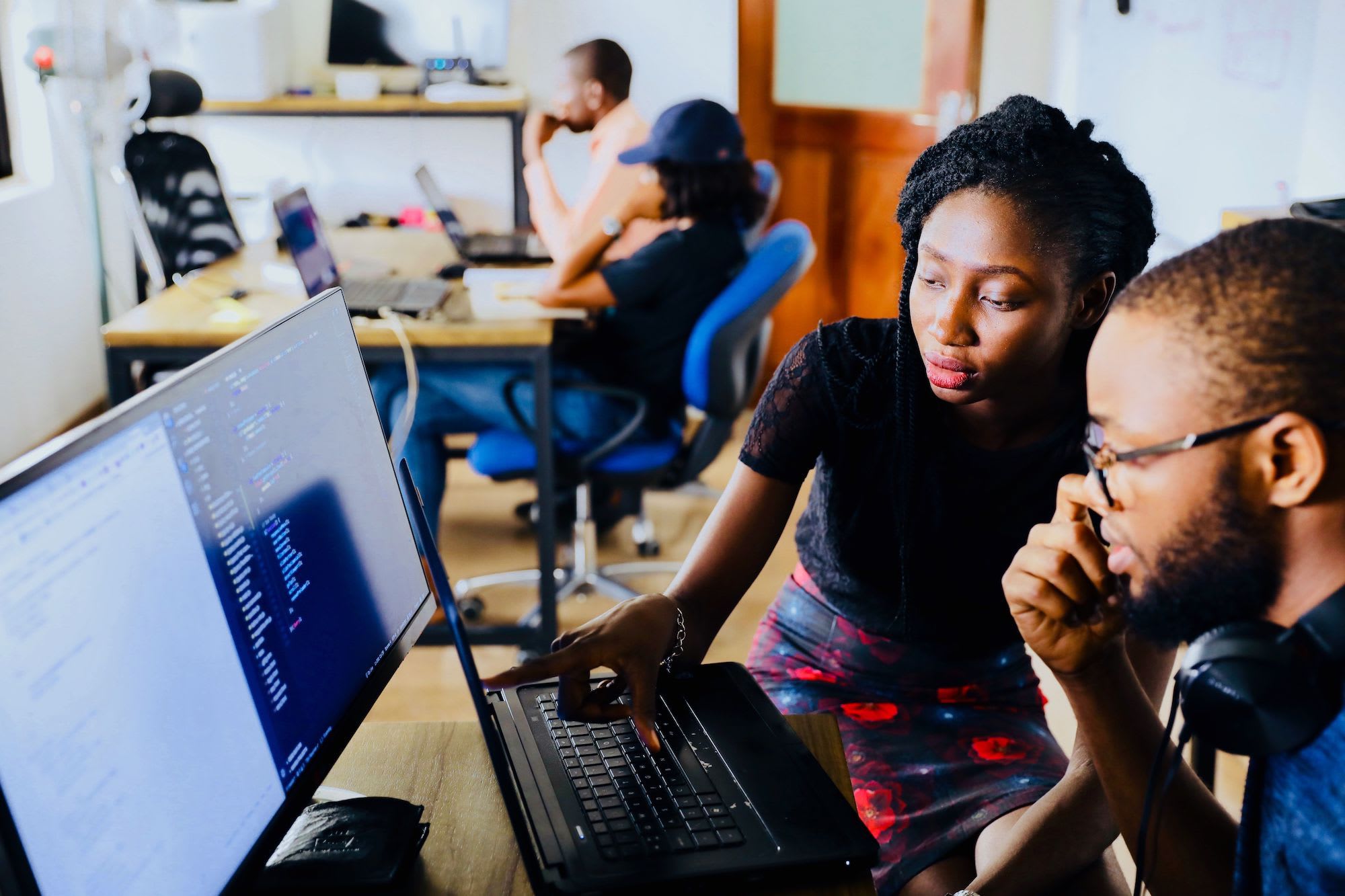 two people in an office looking at a computer screen with code on it