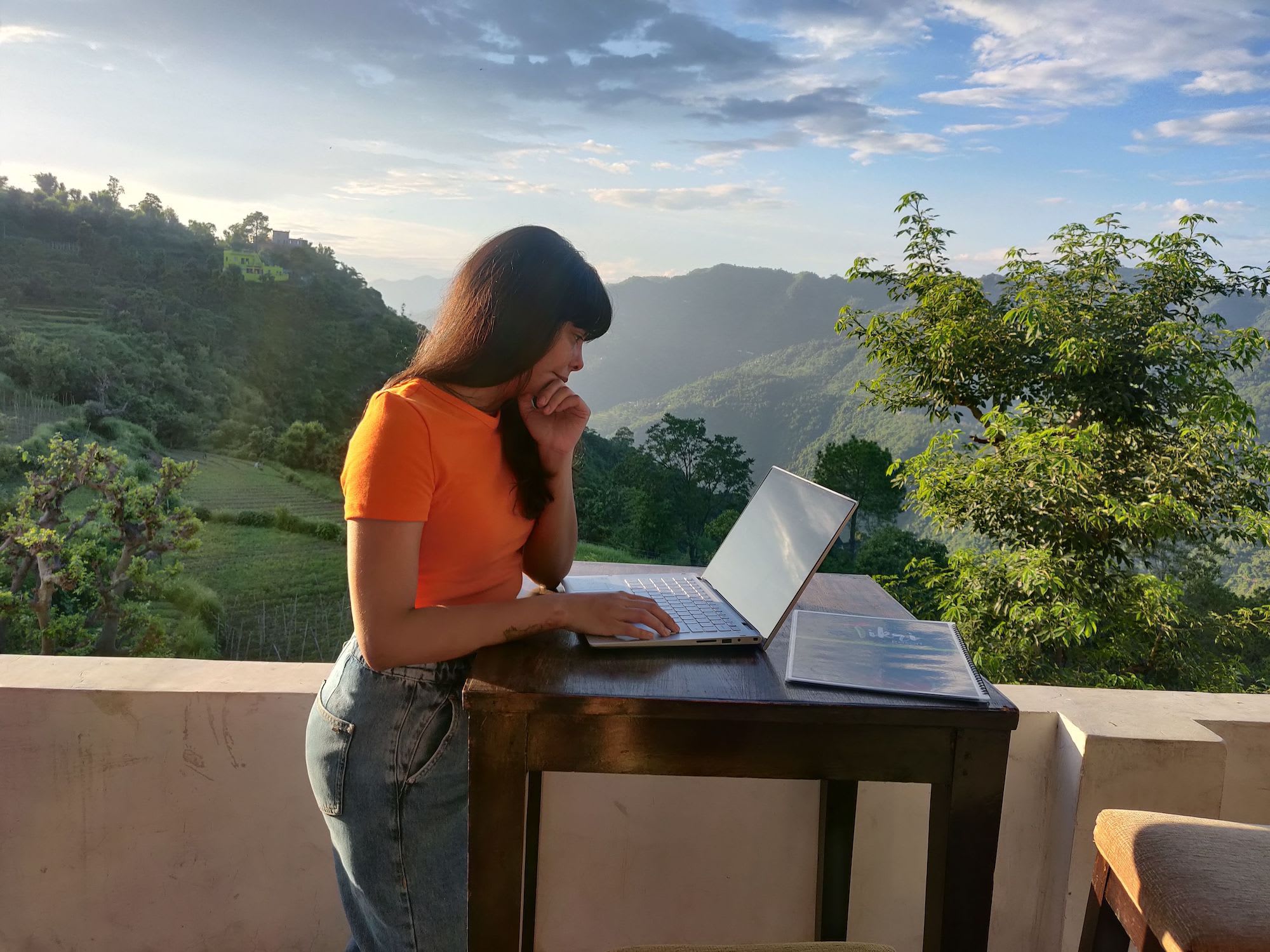 person stood up at a table working on a laptop in a countryside setting