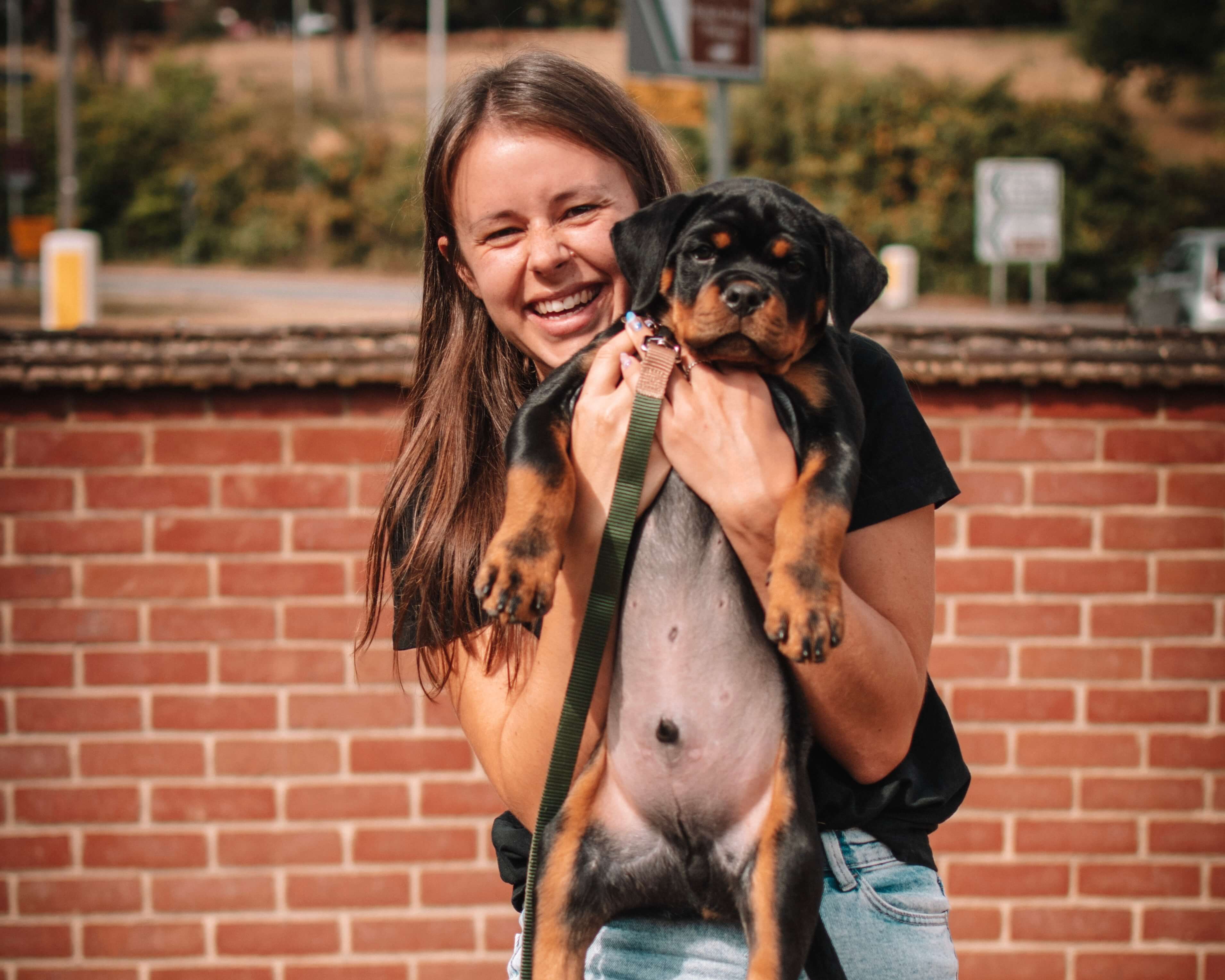 Freestyles frontend web developer Gina Cooper holding up a small rottweiler puppy up to the camera and smiling.