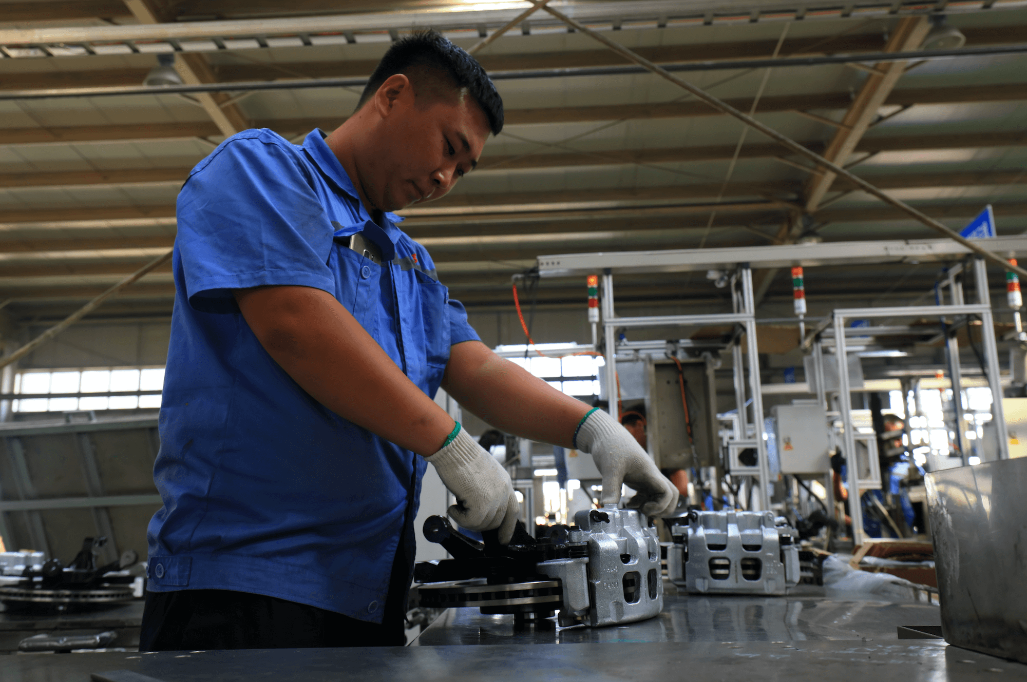 Man working on metal work at a bench with gloves on.