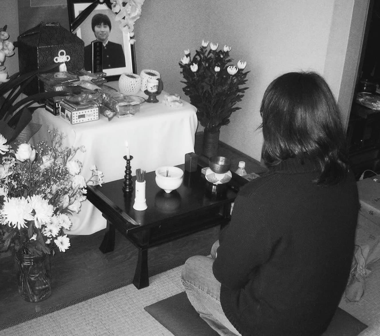 祭壇に飾られた光男君の写真に祈る母親の洋子さん。叔父、光男君、弟、妹の5人で仲良く暮らしていた