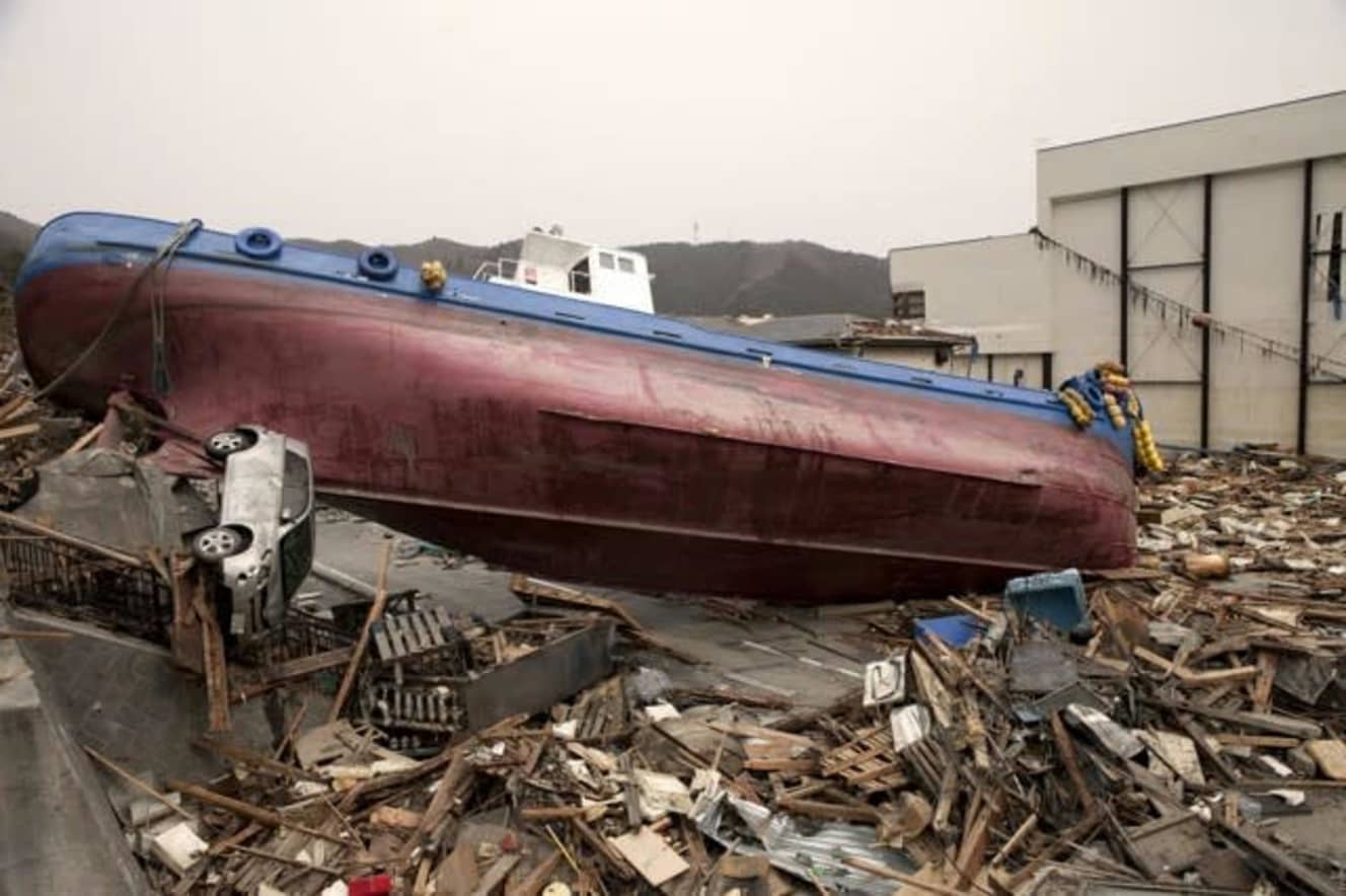 東日本大震災の津波で陸上奥深くまで流された船。左脇に見えるのはミニカーでなく車だ