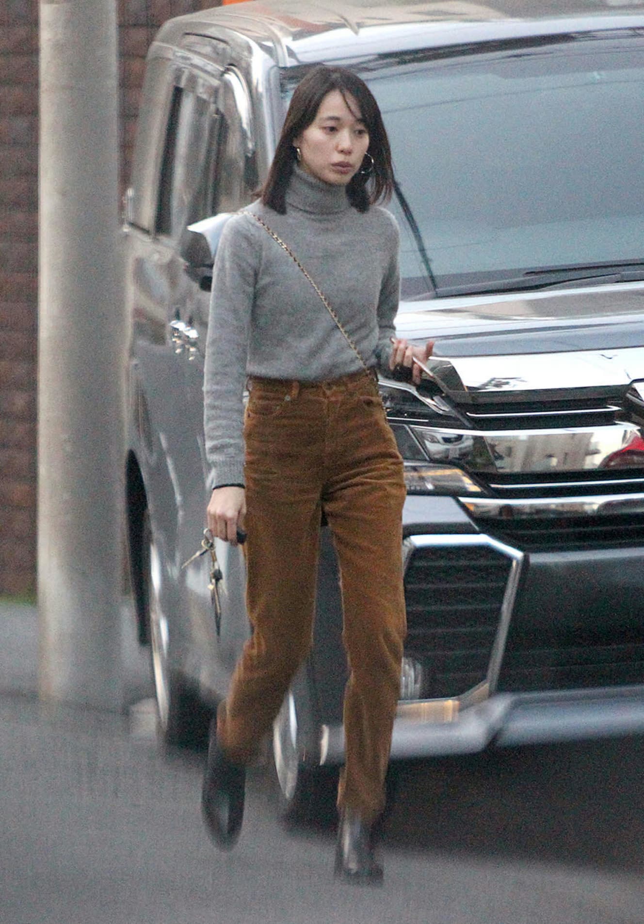 戸田恵梨香はグレーのタートルニット+ブラウンのハイウエストパンツ。フープピアスやチェーンショルダーの斜めがけという、さりげなく女っぽい味つけがキモ(撮影:足立百合)