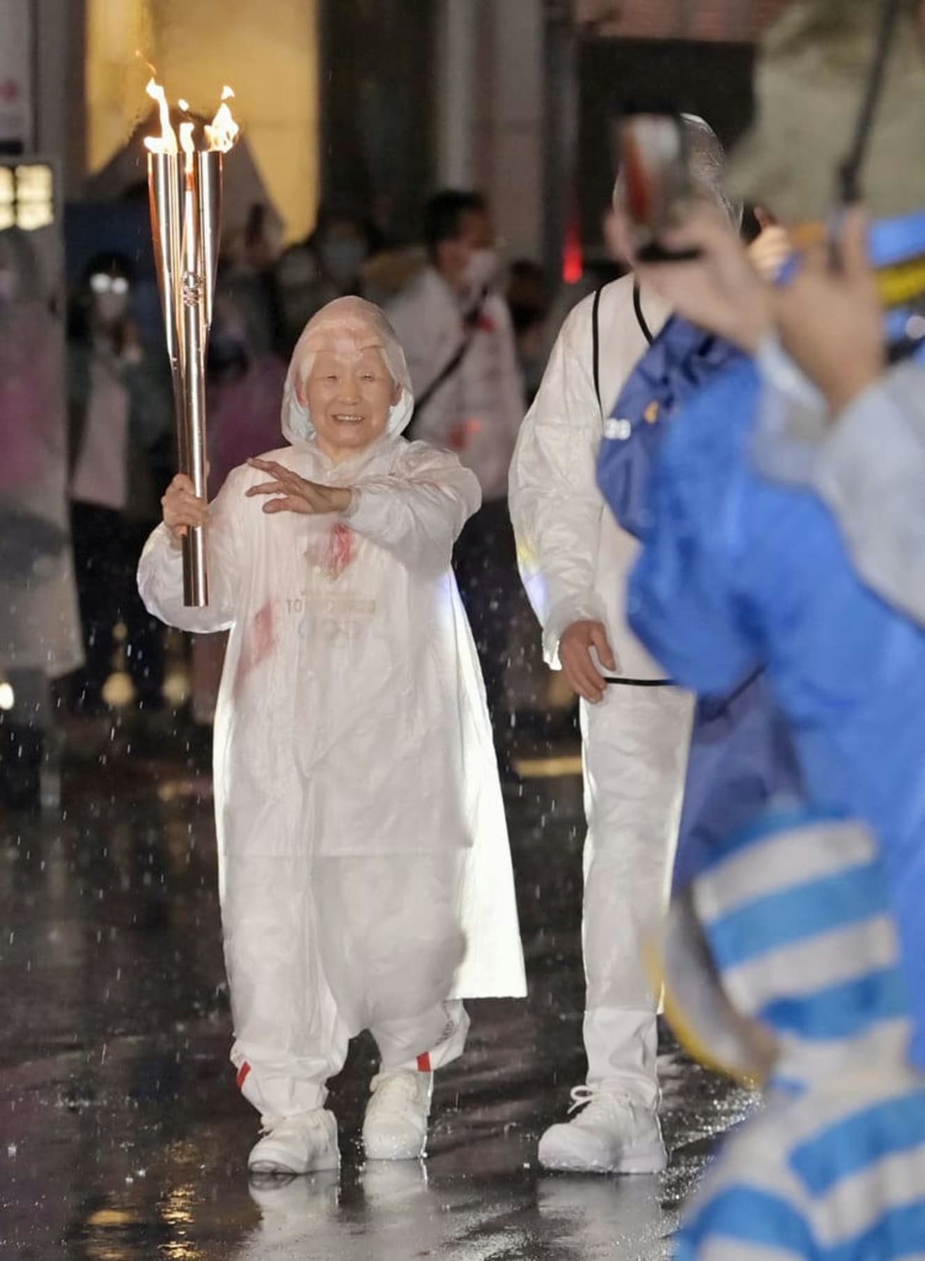 104歳、現役理容師の箱石シツイさんは、雨のなか笑顔で聖火を繋いだ。リレー後「疲れなんてない」と語っていたシツイさんだったが…　写真：共同通信