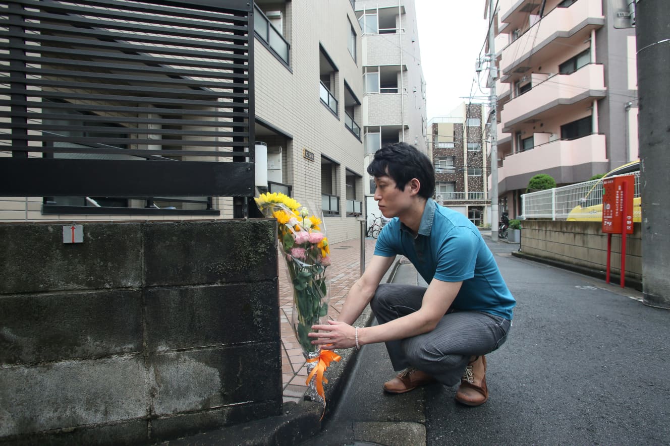 事件現場前に花を供える泰蔵さん(PHOTO/濱崎慎治)