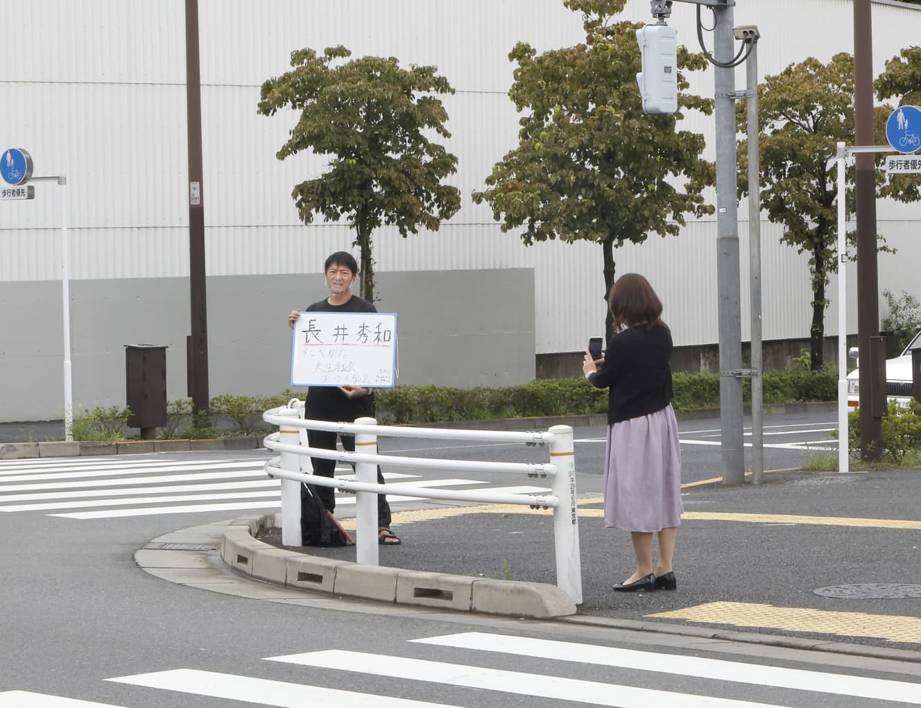 ホワイトボードを持った長井に気づいた女性がスマホのカメラを構えると、笑顔で応じた。知名度はまだまだある