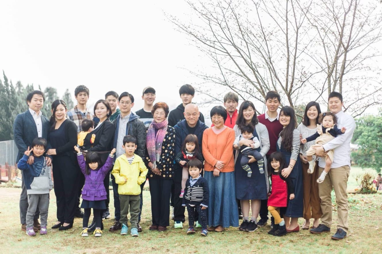 3女の結婚式のときの集合写真。現在、信子さん・英治さん夫婦と、10人の子どもたちの5人の配偶者や13人の甥姪を入れて、岸家は30人! 撮影場所は、きょうだいがピクニックをしたり、早朝にきょうだい全員で水鉄砲大会をした公園(不動さんは、左から4番目)