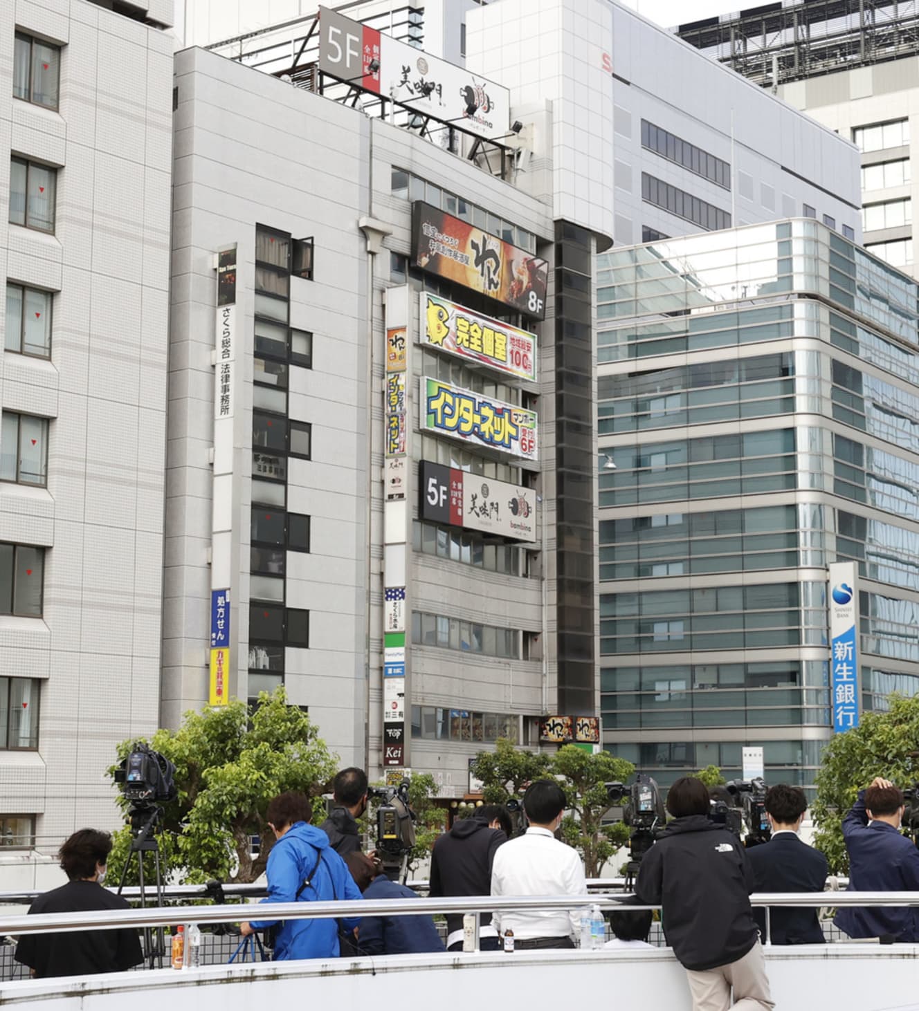 昨年6月18日、さいたま市内で男が女性店員を人質に立てこもったインターネットカフェが入るビル（中央）と集まった報道陣（写真：共同通信）