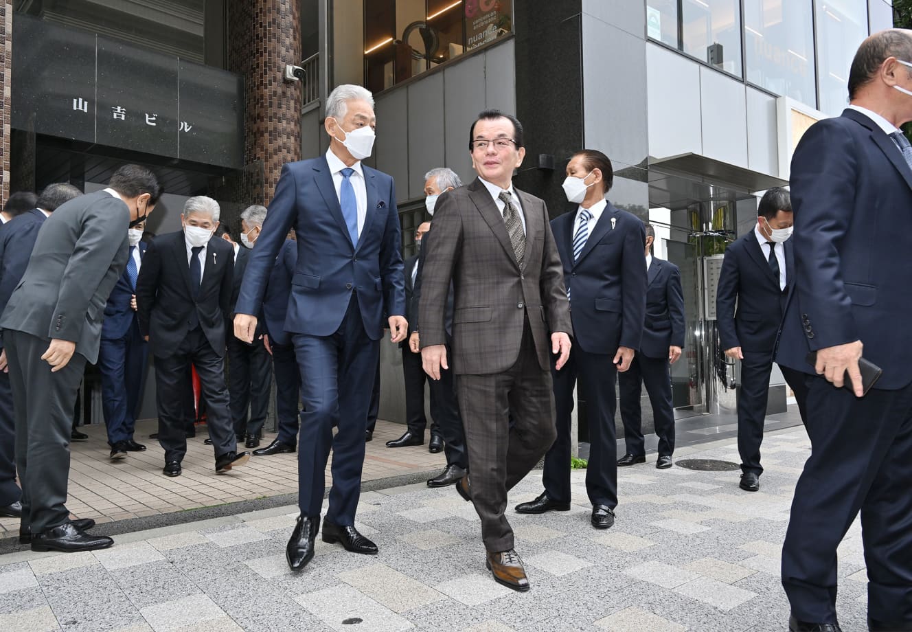 総本部から出てくる道仁会の小林会長（中央右）と稲川会の内堀会長（中央左）。周囲には覆面パトカーの姿も