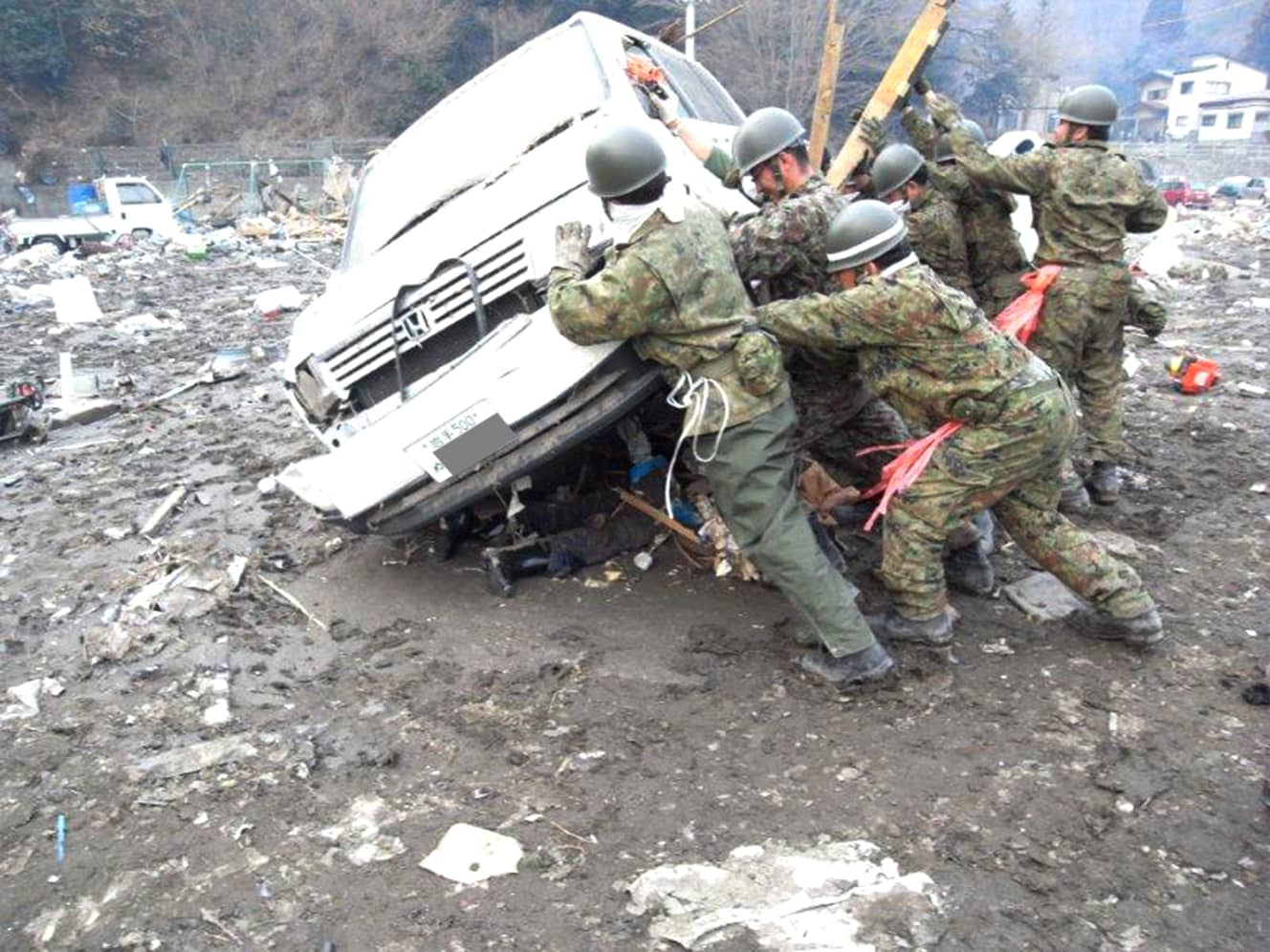 岩手県大槌町の小学校敷地内で自動車の下敷きになった男性を救出しようとする自衛隊員