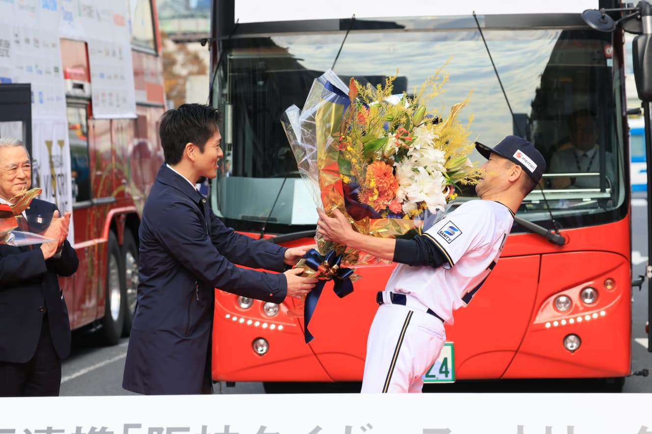 オープニングセレモニーで吉村知事から花束を受け取る中嶋監督。花束が大きかったため、思わずのけぞる形に