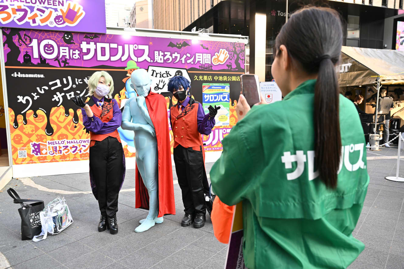 サロンパスの公式キャラクターの『はるお』と写真を撮るコスプレイヤー（左がもんちゅたんさん、右がしろはとさん）