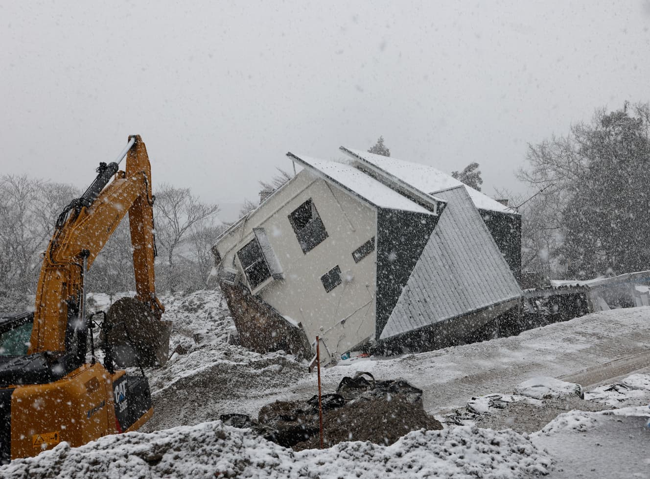 大雪の中、放置される土台からひっくり返った家屋。家の横にはブルーシートが置かれていたが、為す術もない