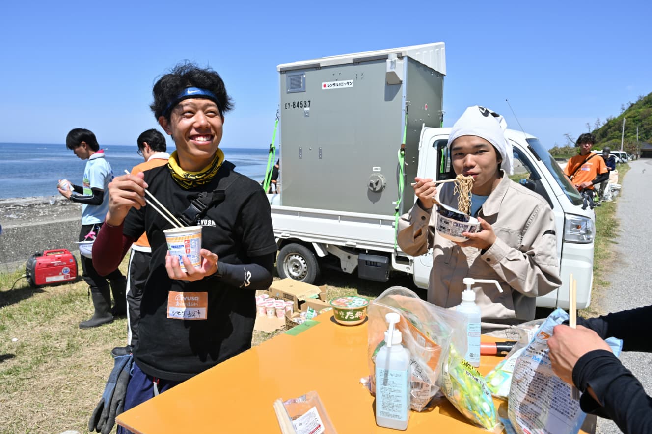 昼食のカップヌードルを食べる。疲れもあるはずだが、カメラを向ければ常に笑顔を見せた