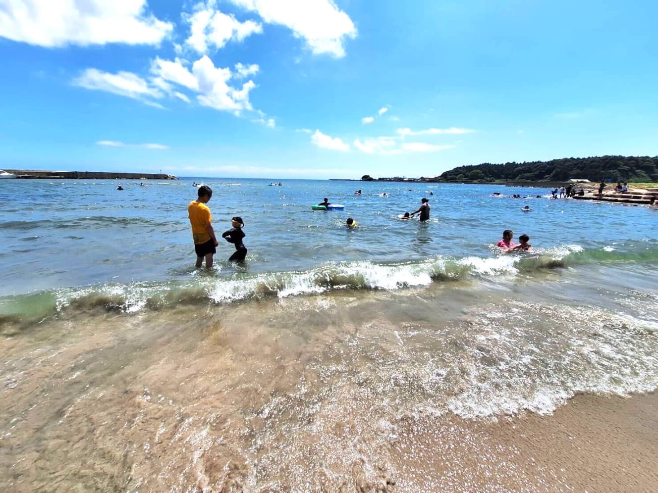 家族連れで賑わう海岸線。大人たちも透き通る極上の海を楽しんでいた