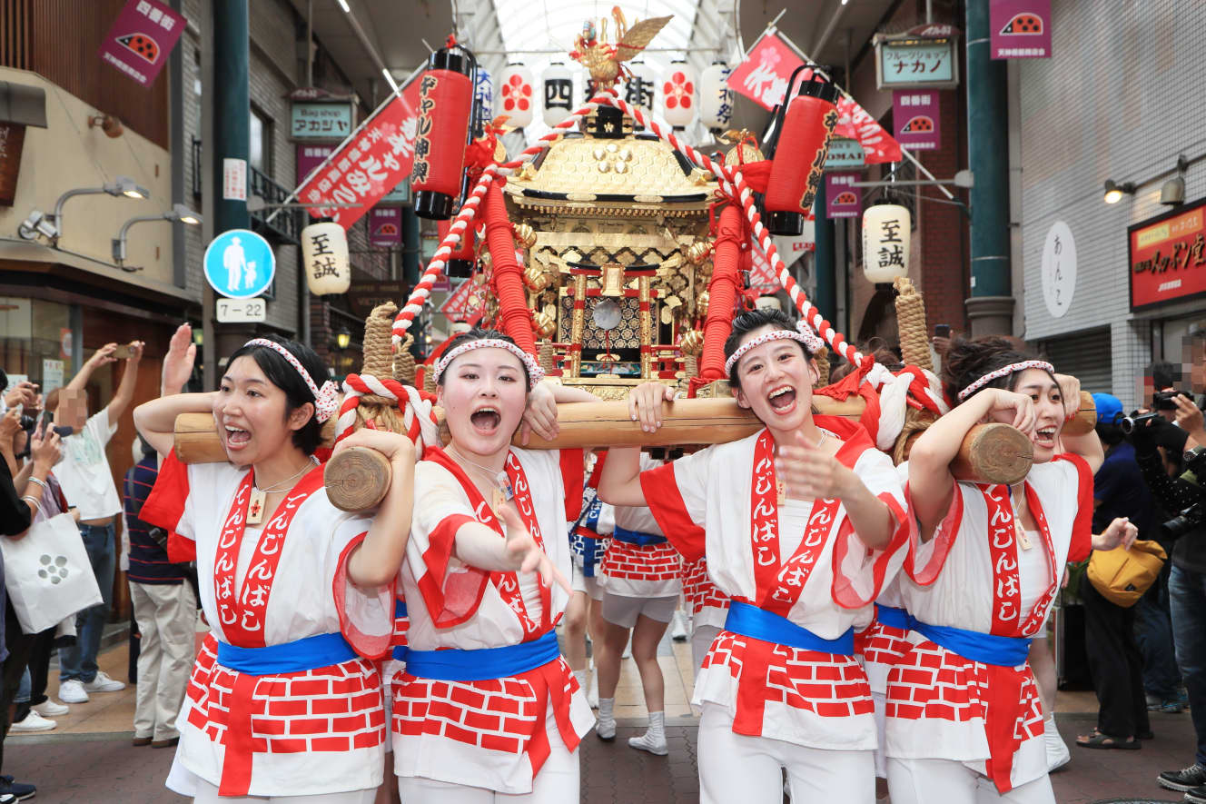 「わっしょい！　わっしょい！」と元気に神輿を担ぐ女性陣。多くの見物客で賑わった