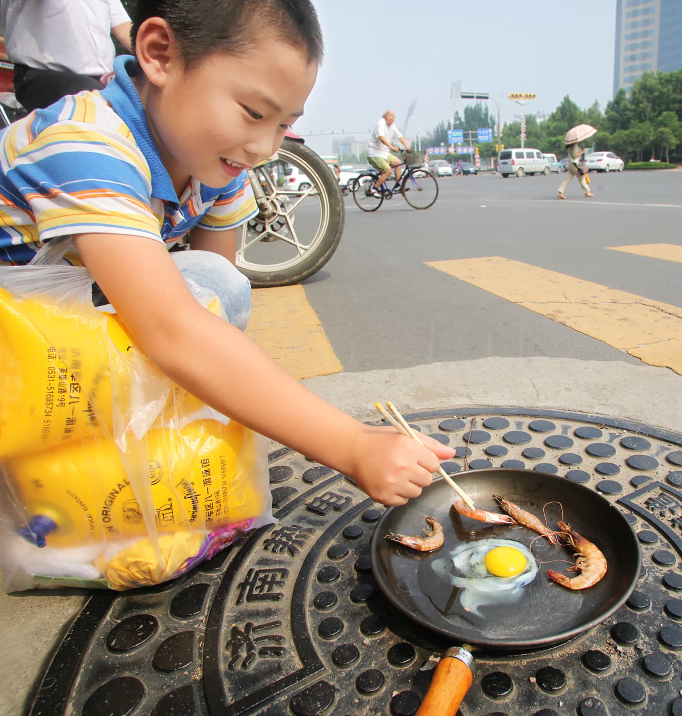 【光熱費のかからない賢い料理法】強い日差しで熱くなった山東省のマンホールで、少年が玉子やエビを焼く