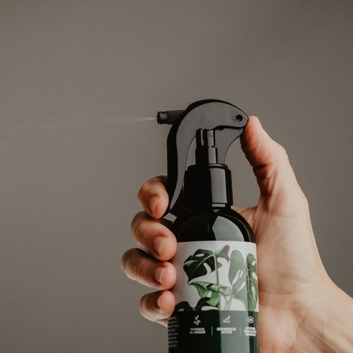 Mano pulverizando fertilizante foliar de marca Fronda