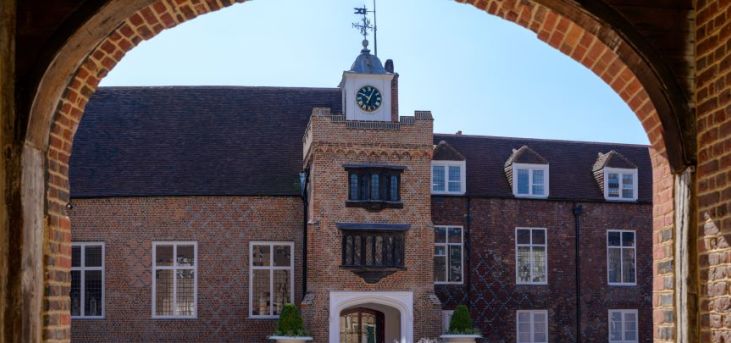 looking into a courtyard from underneath an arch on a sunny day with a fountain in the center