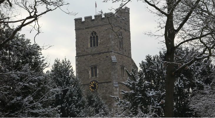 All Saints Fulham church clock surrounded by snowy trees