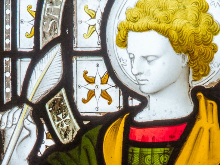 closeup of saint john holding a quill in stained glass