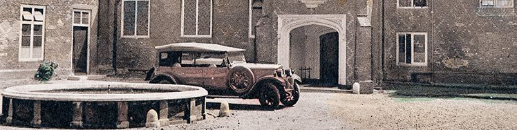 postcard from the 1930s with an automobile parked in the tudor courtyward