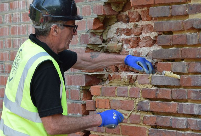 man wearing blue gloves restoring brickwork