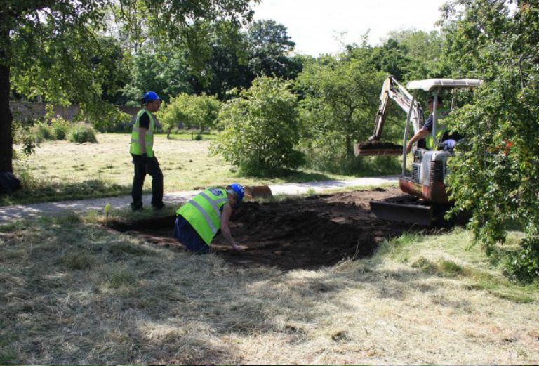 two archaeologists and a digger digging in the walled garden