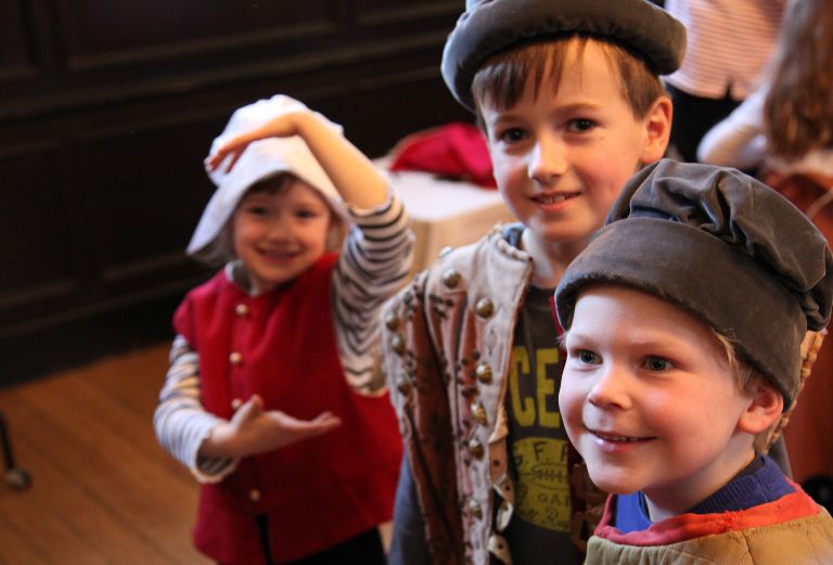 three children dressed in tudor costume smile for the camera