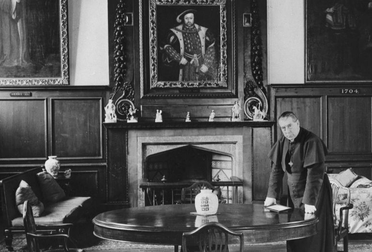 Bishop wand standing with his hands on a round table in the great hall
