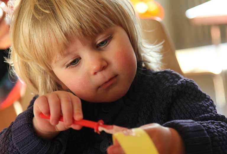 a child gluing paper during a family a craft activity session