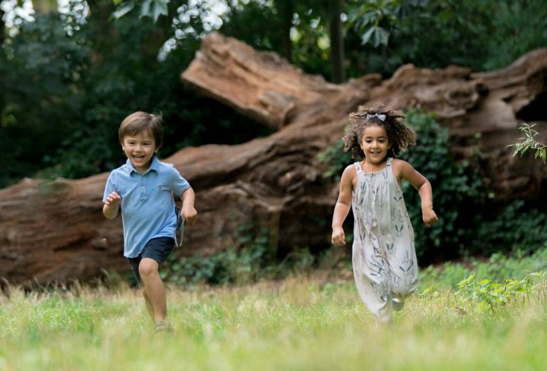 a boy and girl run through the grass smiling