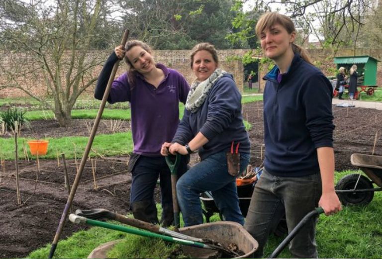 three garden apprentices smiling for a photograph