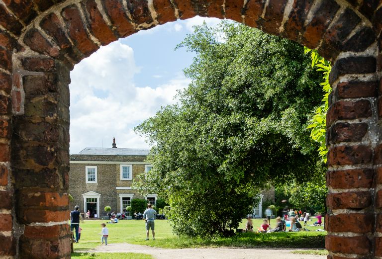 people enjoying the main lawn as seen through the tudor gate of the walled garden