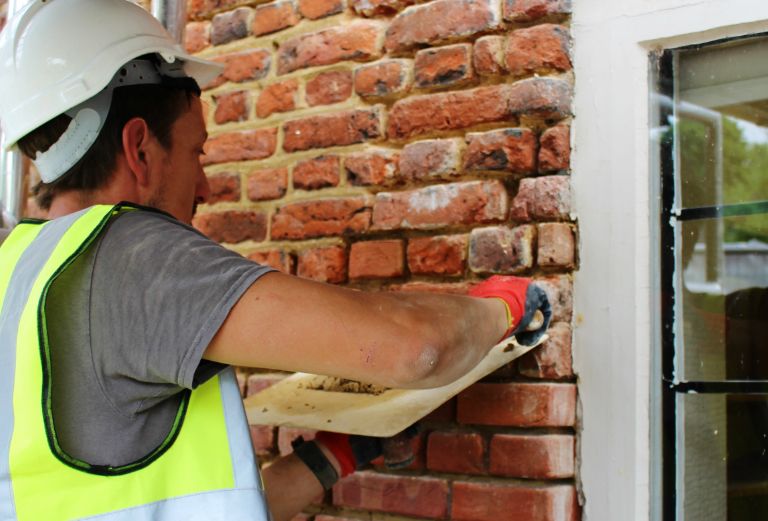 a bricklayer carefully puts mortar between bricks in the tudor courtyard