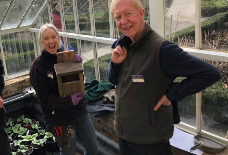 Head gardener Lucy Hart and a garden volunteer pose for a picture with a wooden bird box