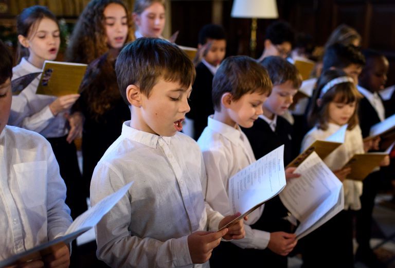 Young children dressed smartly singing from their hymn books.