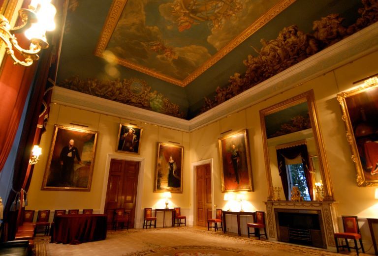 extravagant room with several paintings and a mural on the ceiling
