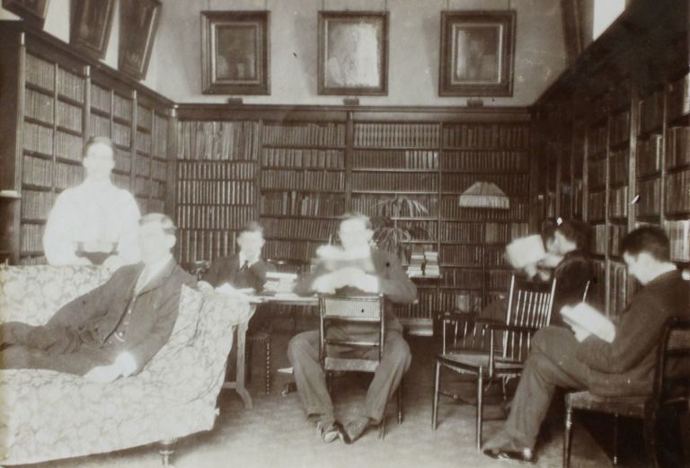 black and white photo of 6 people lounging in a library